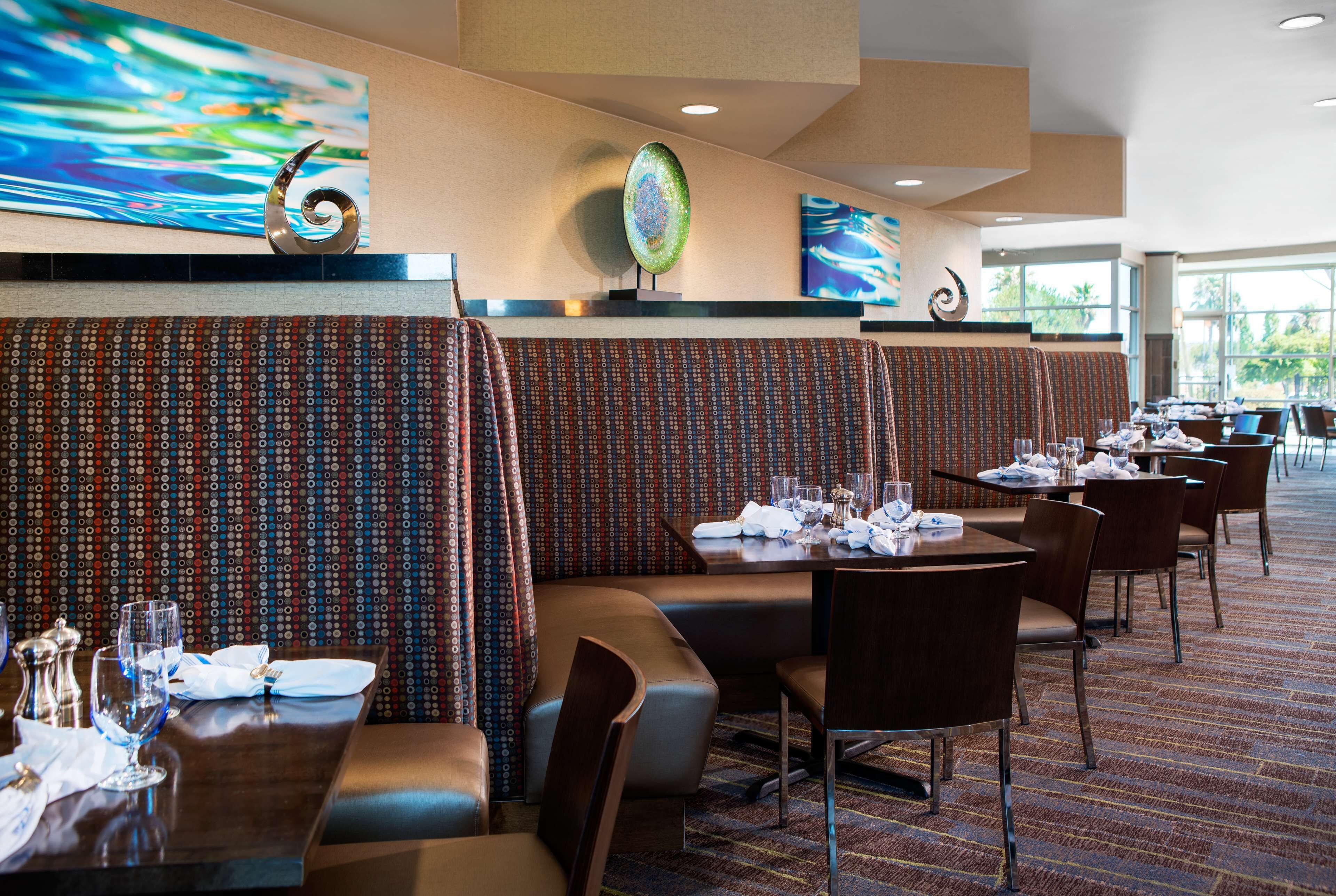 Un restaurant avec des banquettes, des tables et un mur décoré de motifs.