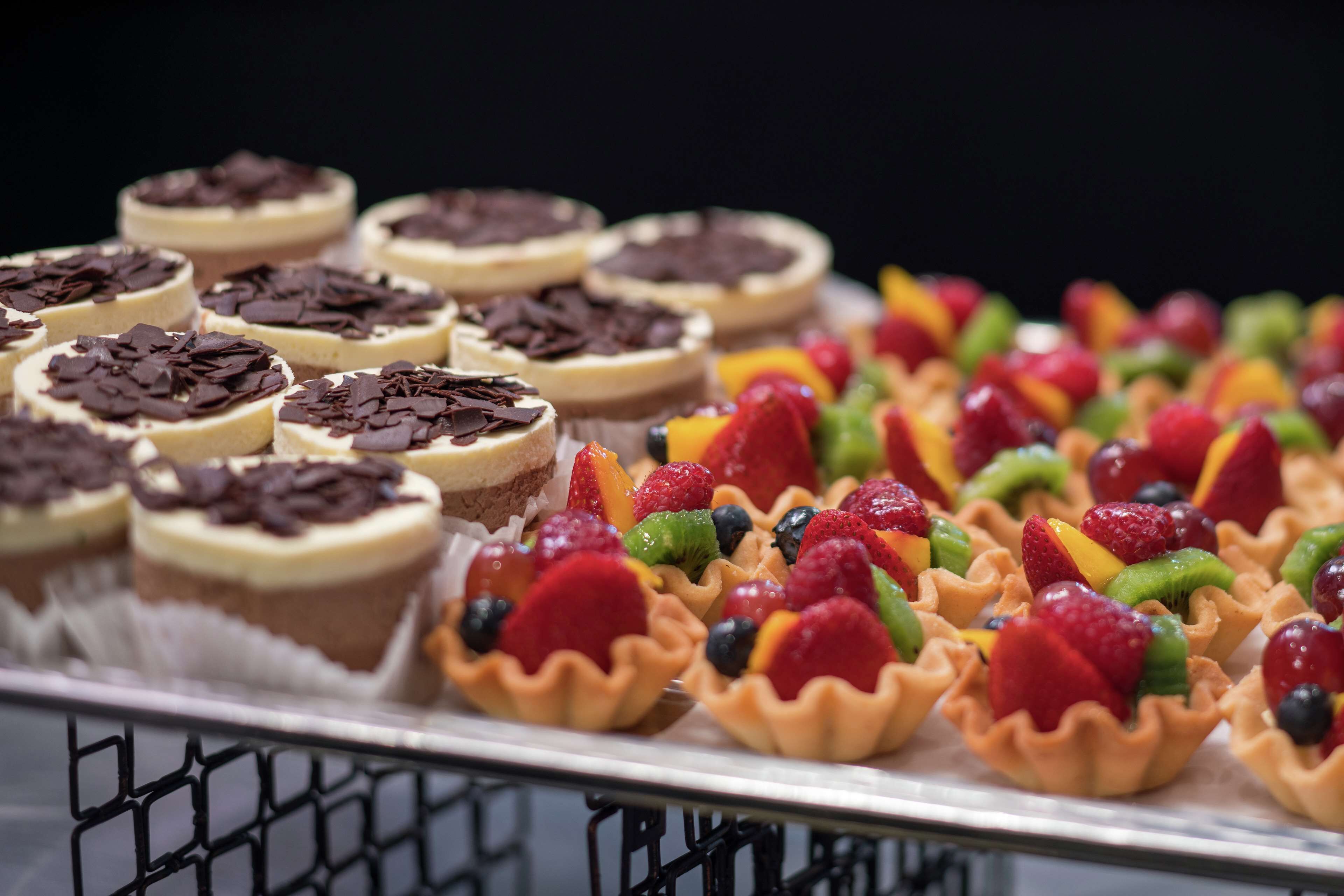 Et fad med forskellige desserter, herunder kager med chokolade og tærter med frugt.