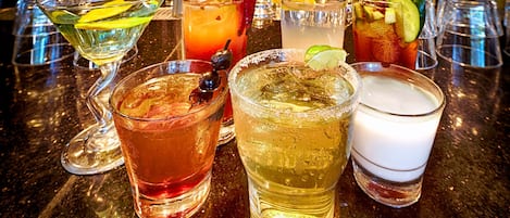 Eine Bar mit verschiedenen Cocktails, Gläsern und einer Theke.