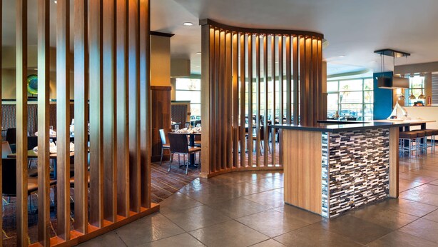 A modern interior with a wooden partition, a stone accent wall, and a bar area.