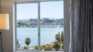 A room with a large window offering a view of a marina and cityscape.