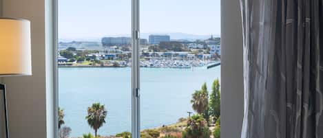 A room with a large window offering a view of a marina and cityscape.