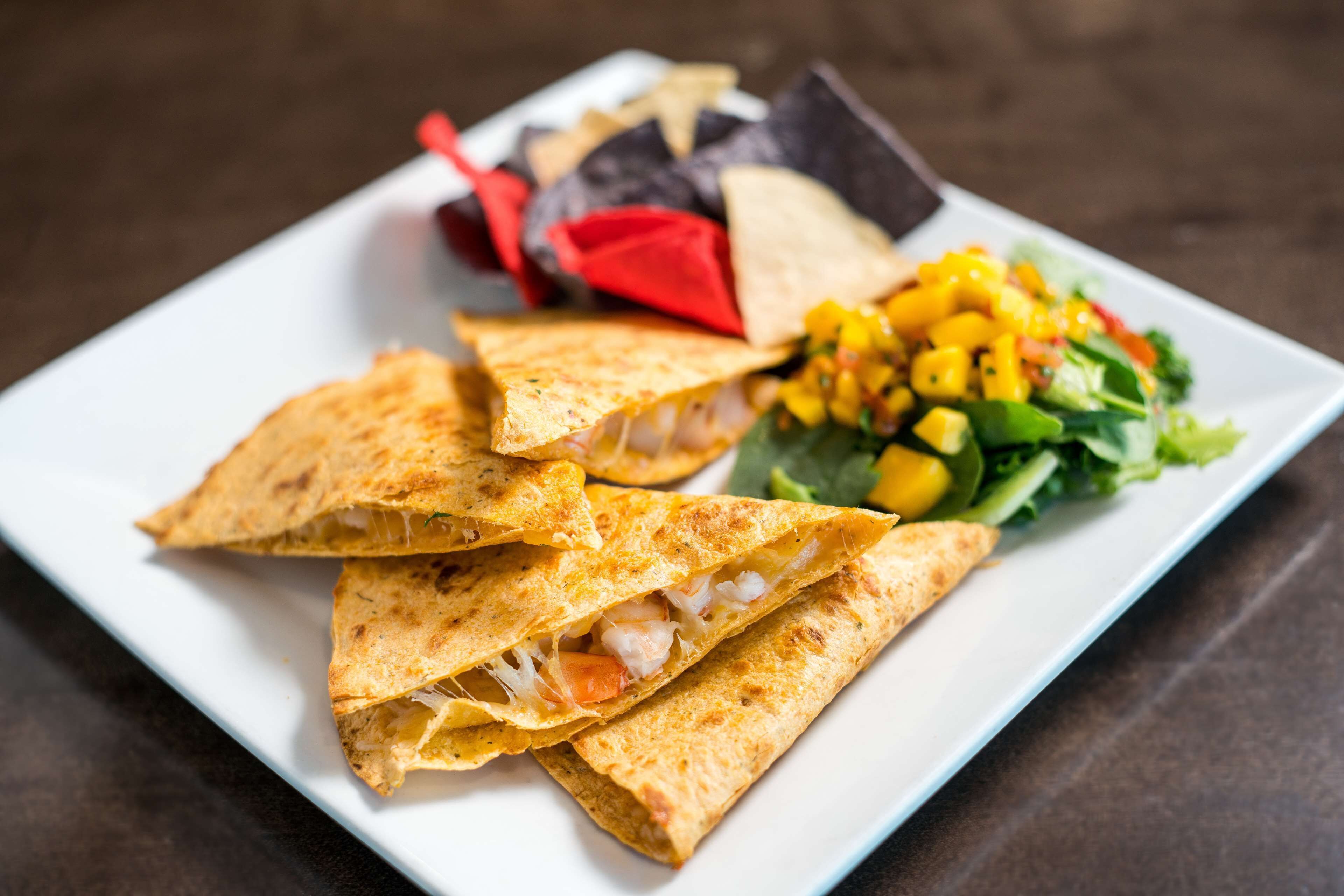 A plate with quesadillas, a side salad, and tortilla chips.