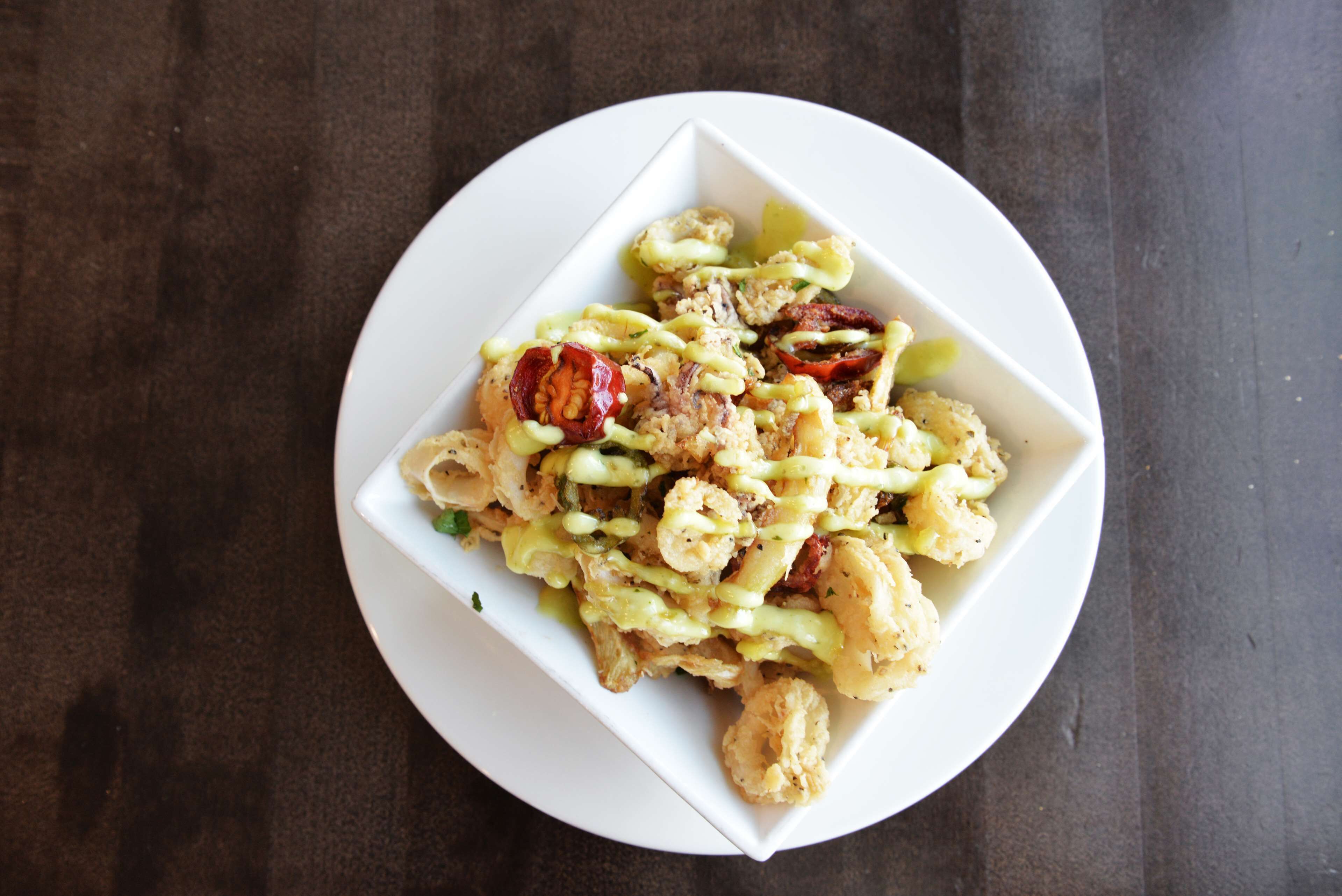 A white plate with a dish containing food items and a drizzle of sauce.