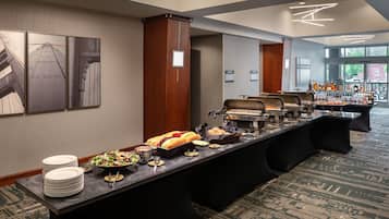 A buffet setup with various food items and a bar area with bottles.