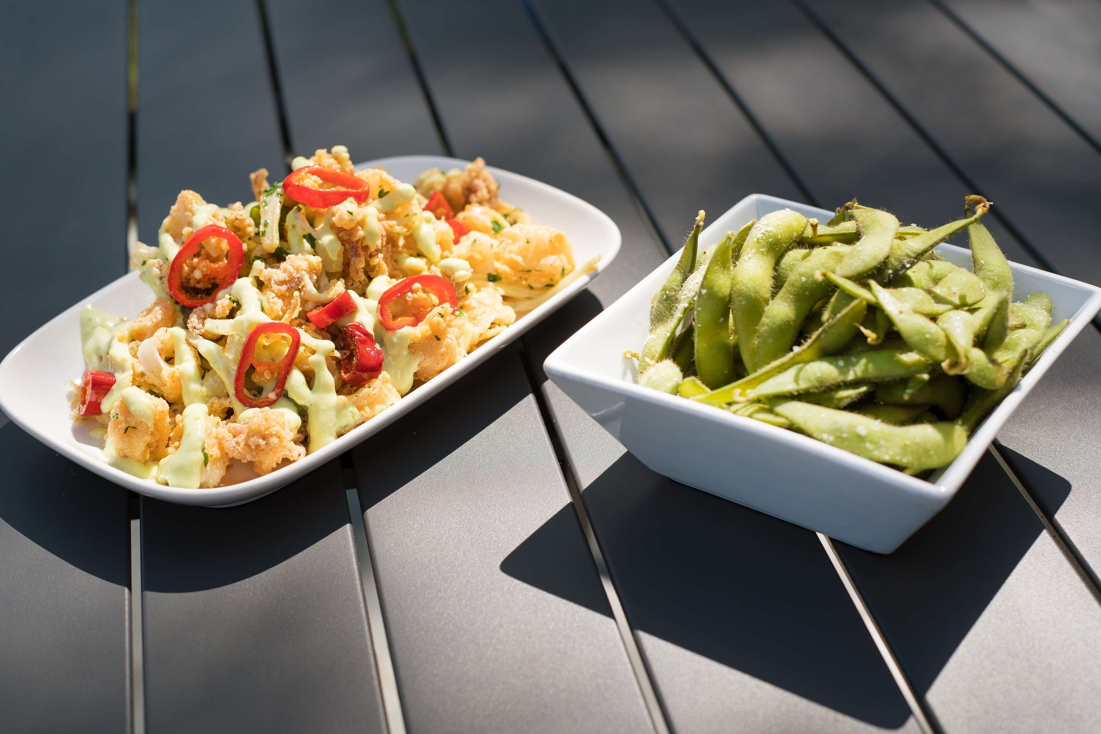 Two dishes on a table: one with a creamy sauce and red peppers, and another with green beans.