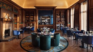 A spacious library with bookshelves, a fireplace, and a bar area. - InterContinental Chantilly Chateau Mont Royal by IHG (La Chapelle-en-Serval)