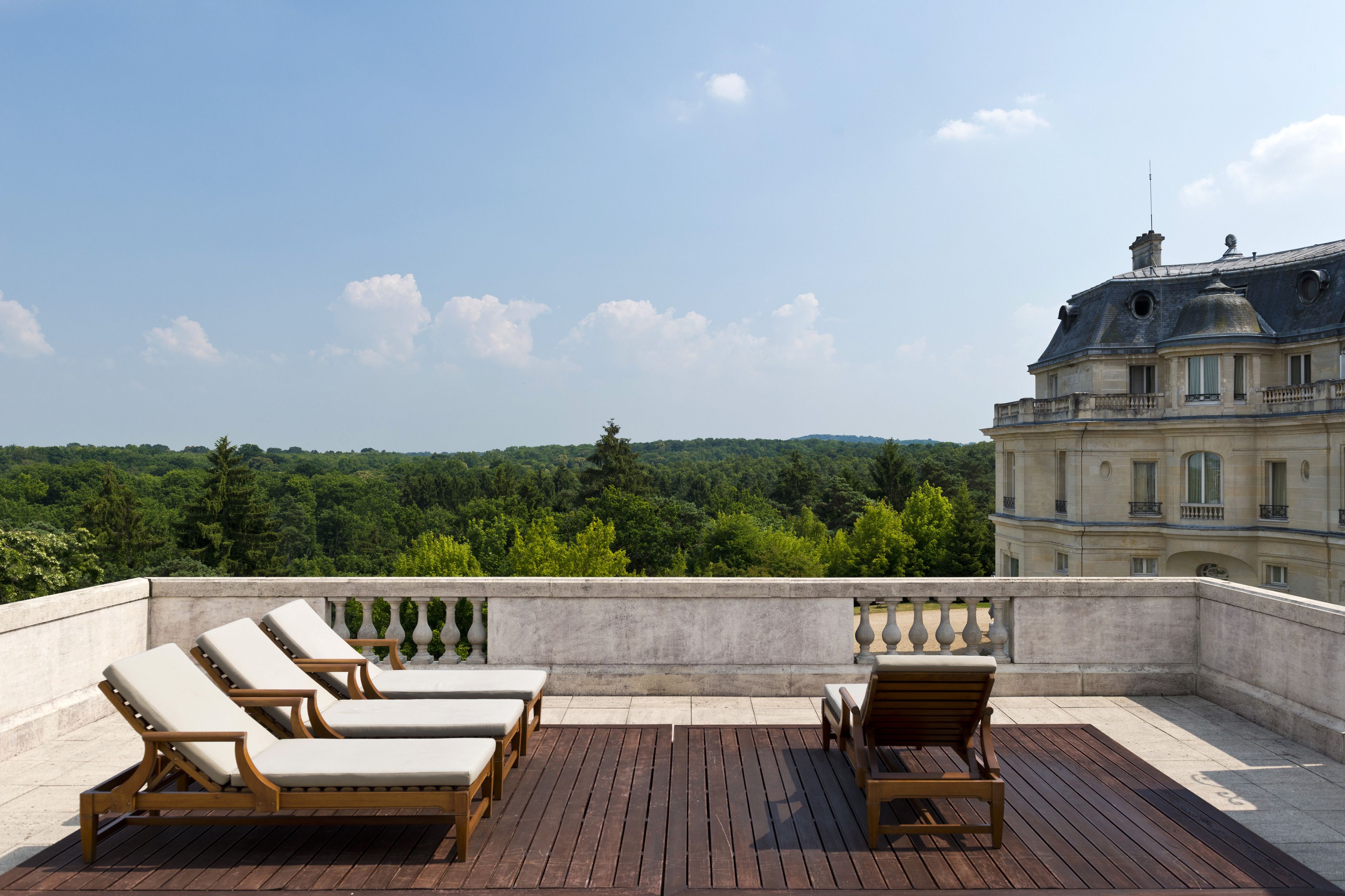 A wooden deck with lounge chairs and a view of a forested area.