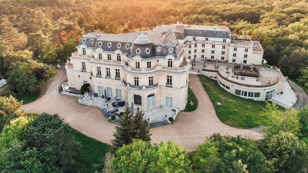 A large, historic building with multiple wings and a central courtyard, surrounded by dense forest. - InterContinental Chantilly Chateau Mont Royal by IHG (La Chapelle-en-Serval)