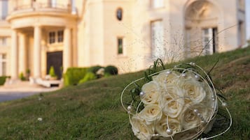 A bouquet of white roses on grass with a classical building in the background.