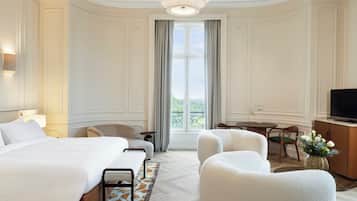 Une chambre d’hôtel avec un grand lit, deux fauteuils, une petite table, une télévision et un balcon avec vue.