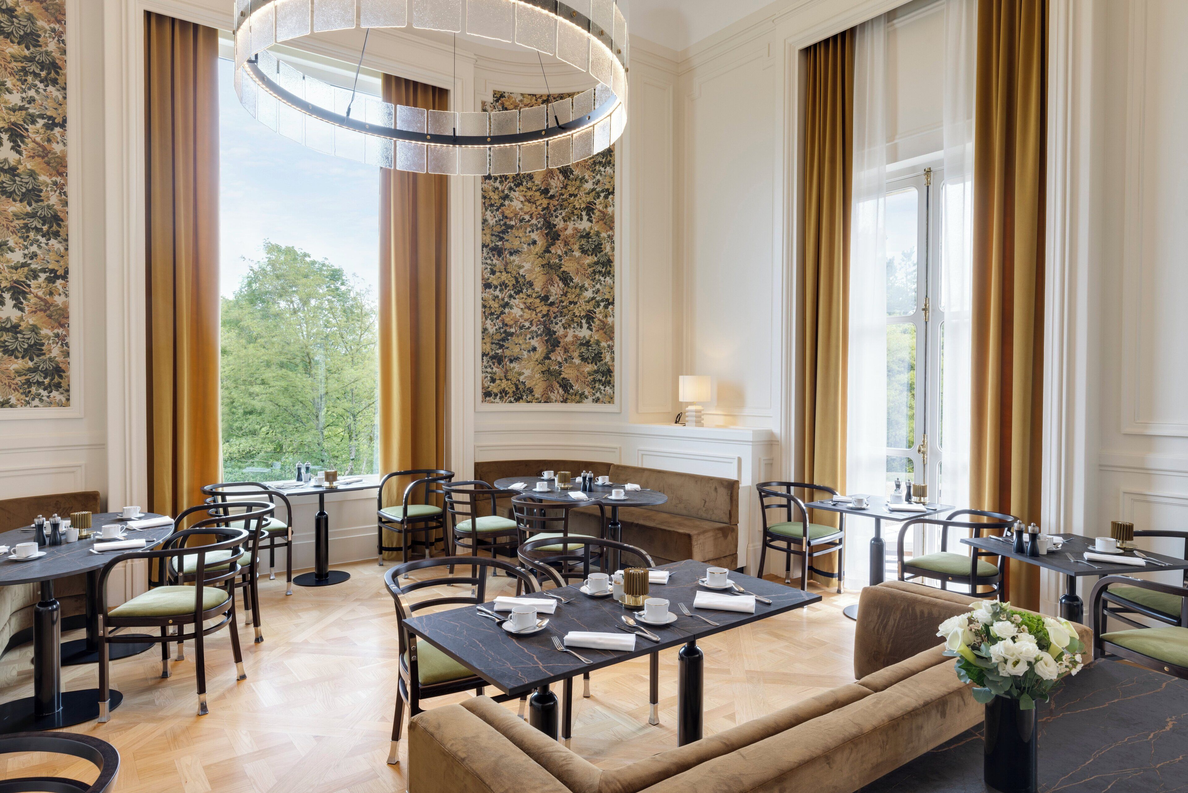 A dining area with round tables, chairs, and a sofa.