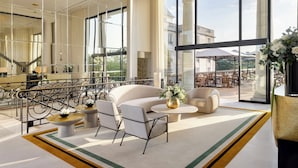 A spacious lobby with a large seating area, a staircase, and large windows offering a view of the outside. - InterContinental Chantilly Chateau Mont Royal by IHG (La Chapelle-en-Serval)