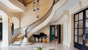 A grand lobby with a marble staircase, a grand piano, and a glass coffee table with a vase of flowers. - InterContinental Chantilly Chateau Mont Royal by IHG (La Chapelle-en-Serval)