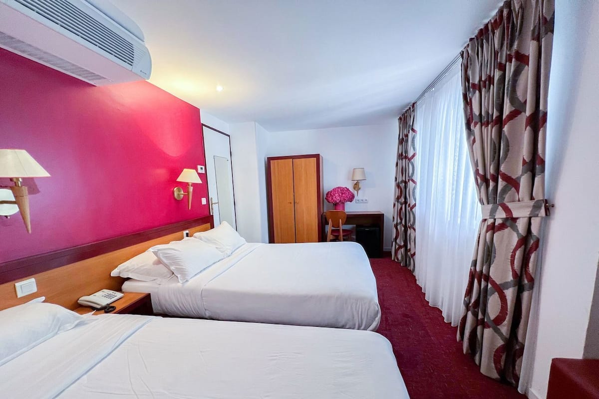 Una habitación de hotel con dos camas, un escritorio, una silla, un armario y baño.