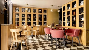 A dining area with wooden cabinets and chairs, a checkered floor, and a laptop on a table. - La Dépendance (Paris)