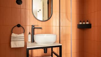 A bathroom with a white sink, black vanity, a towel rack, a mirror, and a shelf with toiletries.