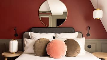A bed with multiple pillows, a round mirror above it, and two bedside tables with lamps.