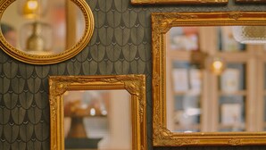 A room with a patterned wallpaper, a red upholstered bench, and three framed mirrors. - La Dépendance (Paris)