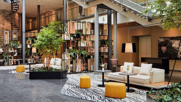 A spacious atrium with a glass ceiling, multiple levels, and a central staircase. - NH Collection Heidelberg (Heidelberg)