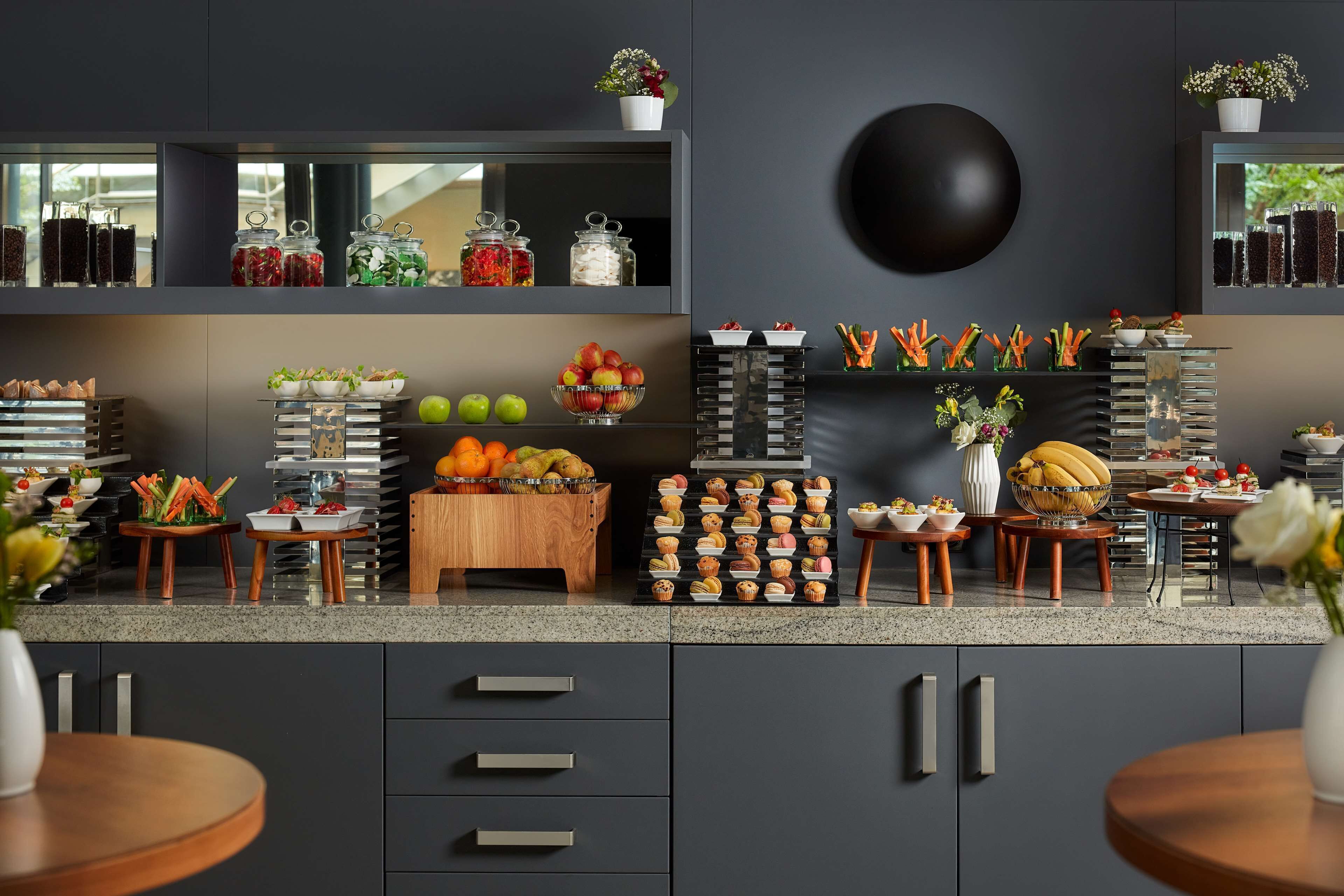 Una cocina moderna con encimera de granito, diversos alimentos y un altavoz negro grande fijado a la pared.