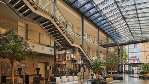 A spacious atrium with a high ceiling, a staircase, and a seating area with a sofa and ottoman.