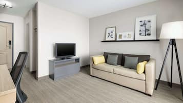 Una habitación de hotel moderna con sofá, televisión y una obra de arte en la pared.