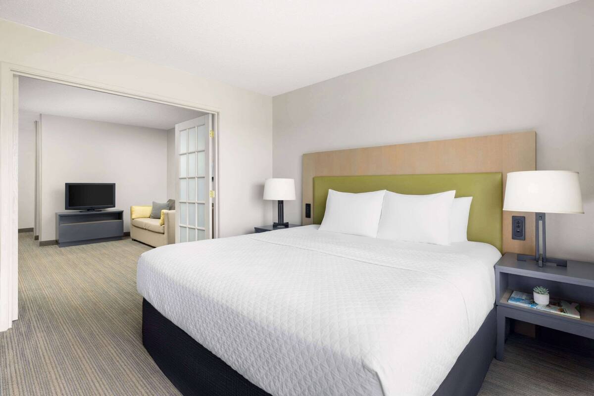 Une chambre d’hôtel avec un grand lit, une télévision, un canapé et un bureau avec une lampe.