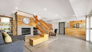 Un vaste espace de vie comprenant un escalier, une cheminée et un comptoir d’accueil en bois.