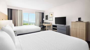 A hotel room with two beds, a desk, a TV, and a wardrobe.