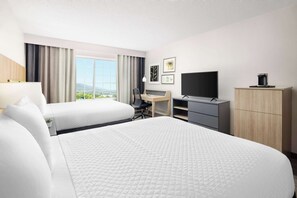A hotel room with two beds, a desk, a TV, and a wardrobe.