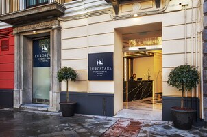 La entrada del Hotel Eurostars Puerta Real, con un puerta de cristal, plantas en macetas y un mostrador de recepción a la vista.