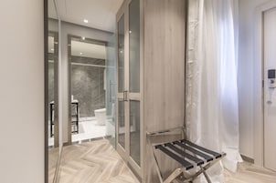 A modern bathroom with a glass shower enclosure, a wooden vanity, and a towel rack.