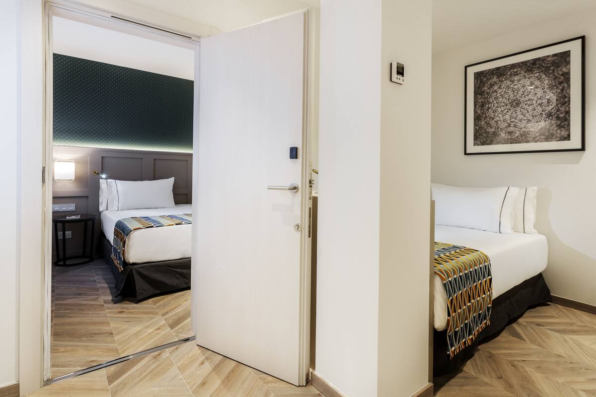 A hotel room with a bed, bedside table, and a wall-mounted artwork.