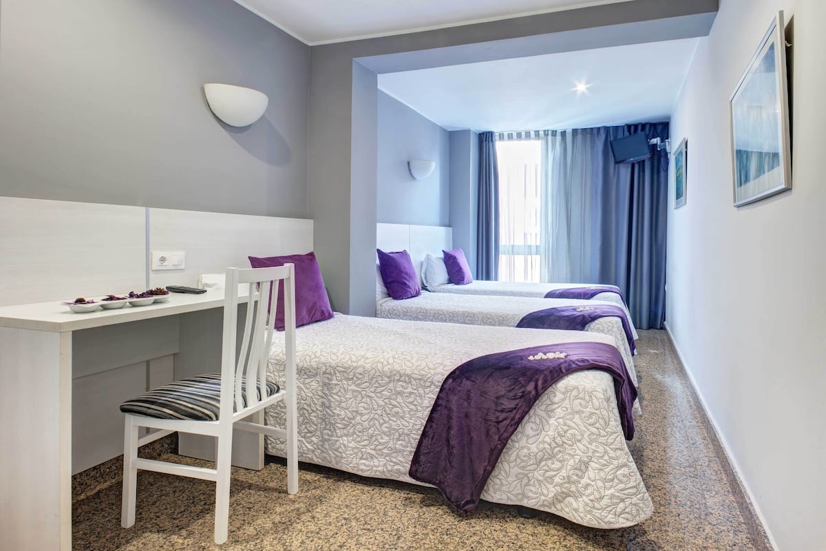 A hotel room with two beds, a desk, and a chair.