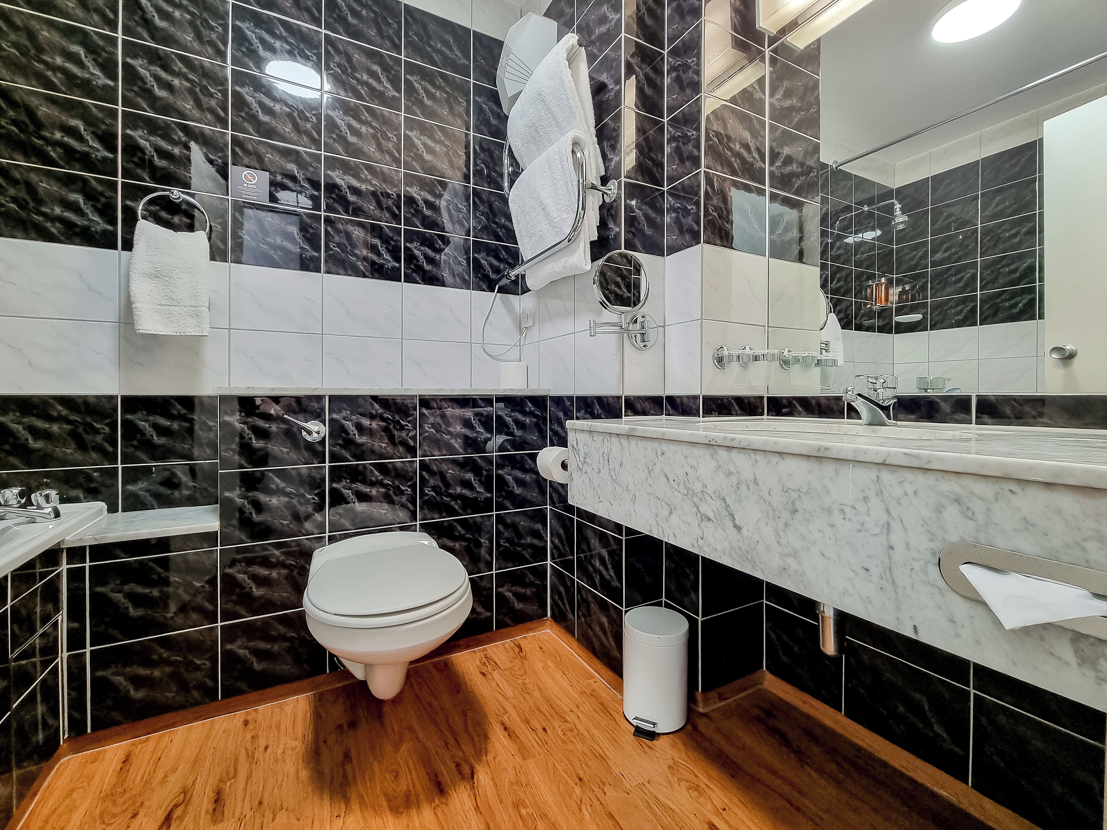 A modern bathroom with a marble backsplash, a toilet, a sink, and a mirror.