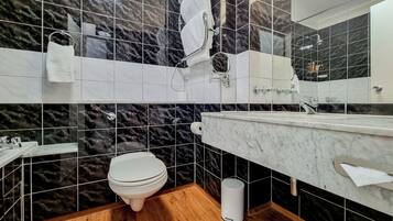 A modern bathroom with a marble backsplash, a toilet, a sink, and a mirror.