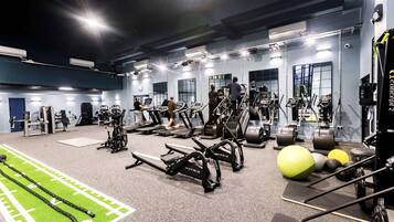 Un gimnasio con cintas de correr, elípticas y pesas sueltas.