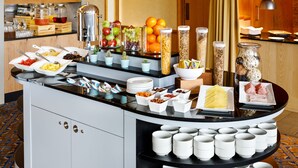 Un bufé con diversos alimentos y bebidas, como frutas, quesos y cereales.