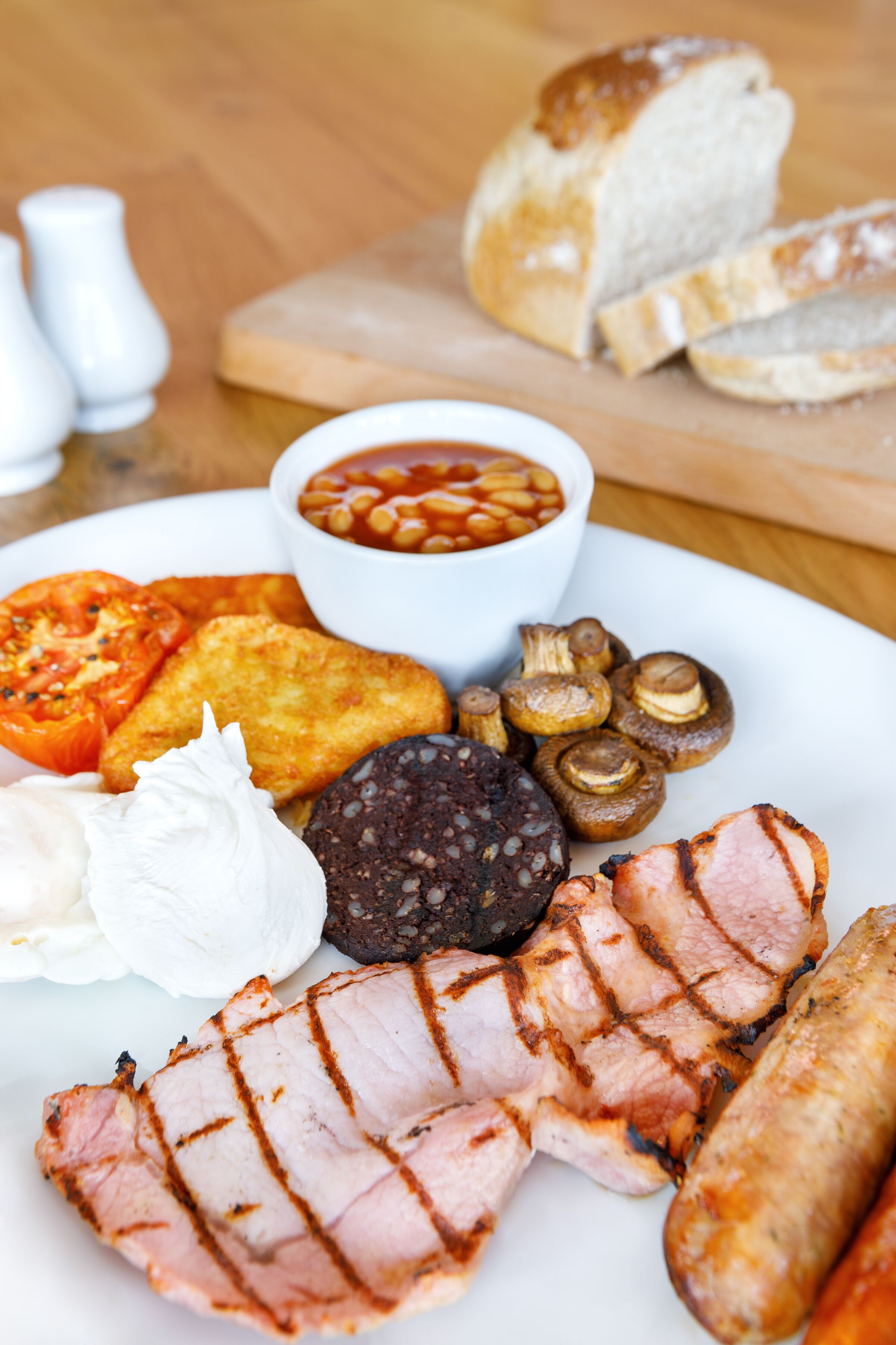A plate of food including grilled meat, sausages, mushrooms, and beans.