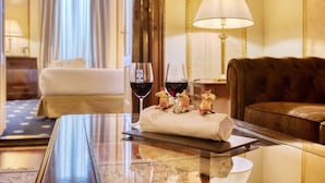 A hotel room with a glass table, two wine glasses, a small decorative item, a sofa, and a lamp. - Hotel Roger de Lluria Barcelona (Barcelona)