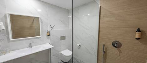 Une salle de bain moderne avec une douche à parois de verre, un lavabo blanc et un meuble-lavabo en bois.