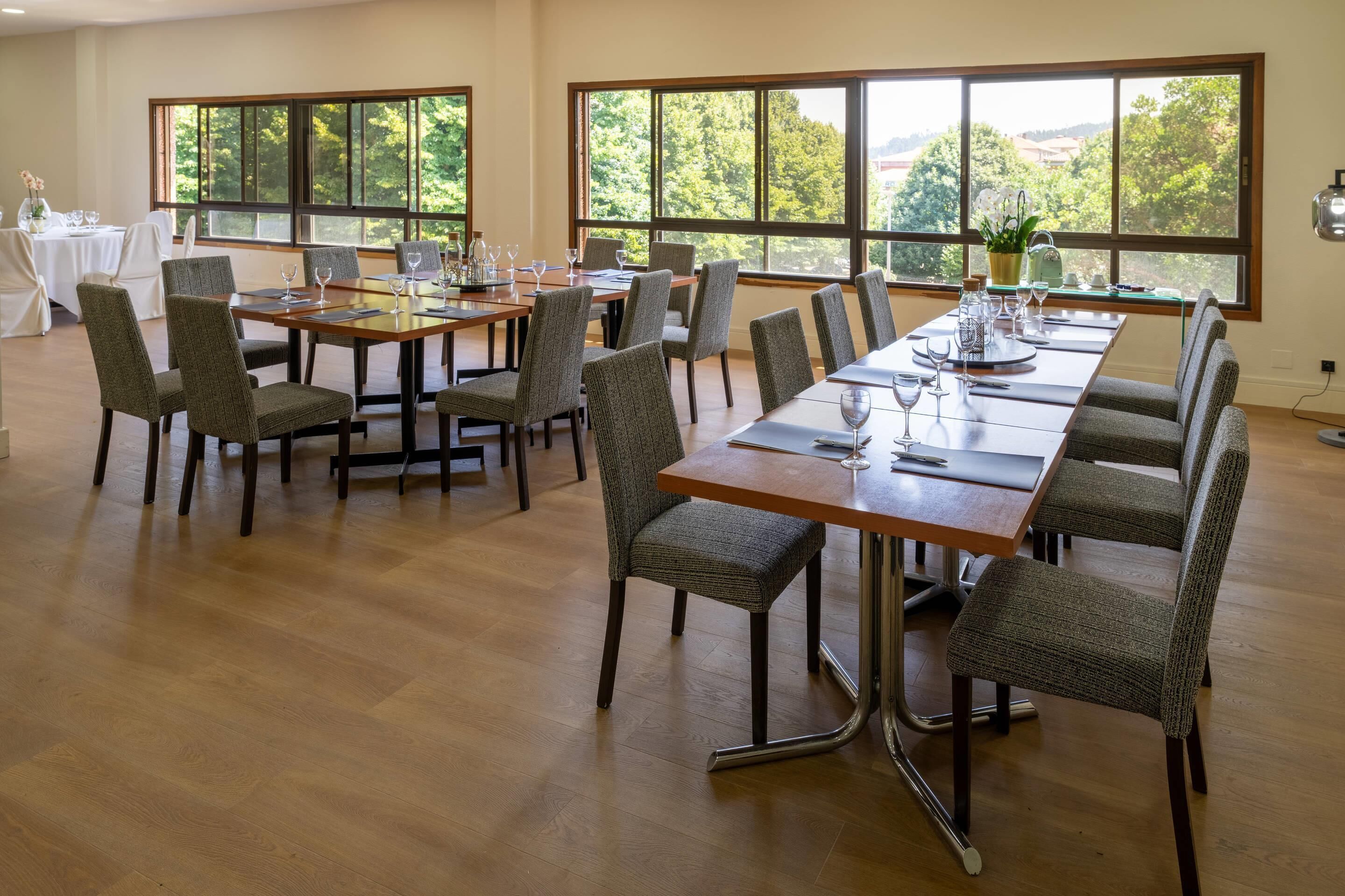 Un comedor con ventanas amplias, mesas de madera y sillas tapizadas.