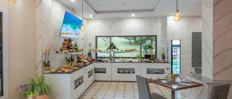 Una cocina moderna con una isla grande, un comedor con mesas y sillas, y un ventanal que ofrece vistas al exterior.