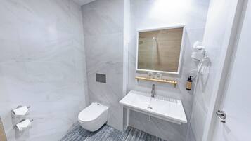 Un baño moderno con inodoro blanco, lavamanos y zona de ducha.