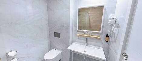 A modern bathroom with a white toilet, a sink, and a shower area.