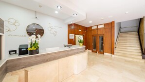 A reception area with a wooden reception desk, a large wall clock, and a staircase leading to an upper floor. - Hotel Faranda Los Tilos, Ascend Hotel Collection (Teo)
