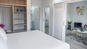 A modern hotel room with a large bed, a walk-in closet, a bathroom with a glass shower, and a living area with a zebra-patterned rug. - Hotel Faranda Los Tilos, Ascend Hotel Collection (Teo)
