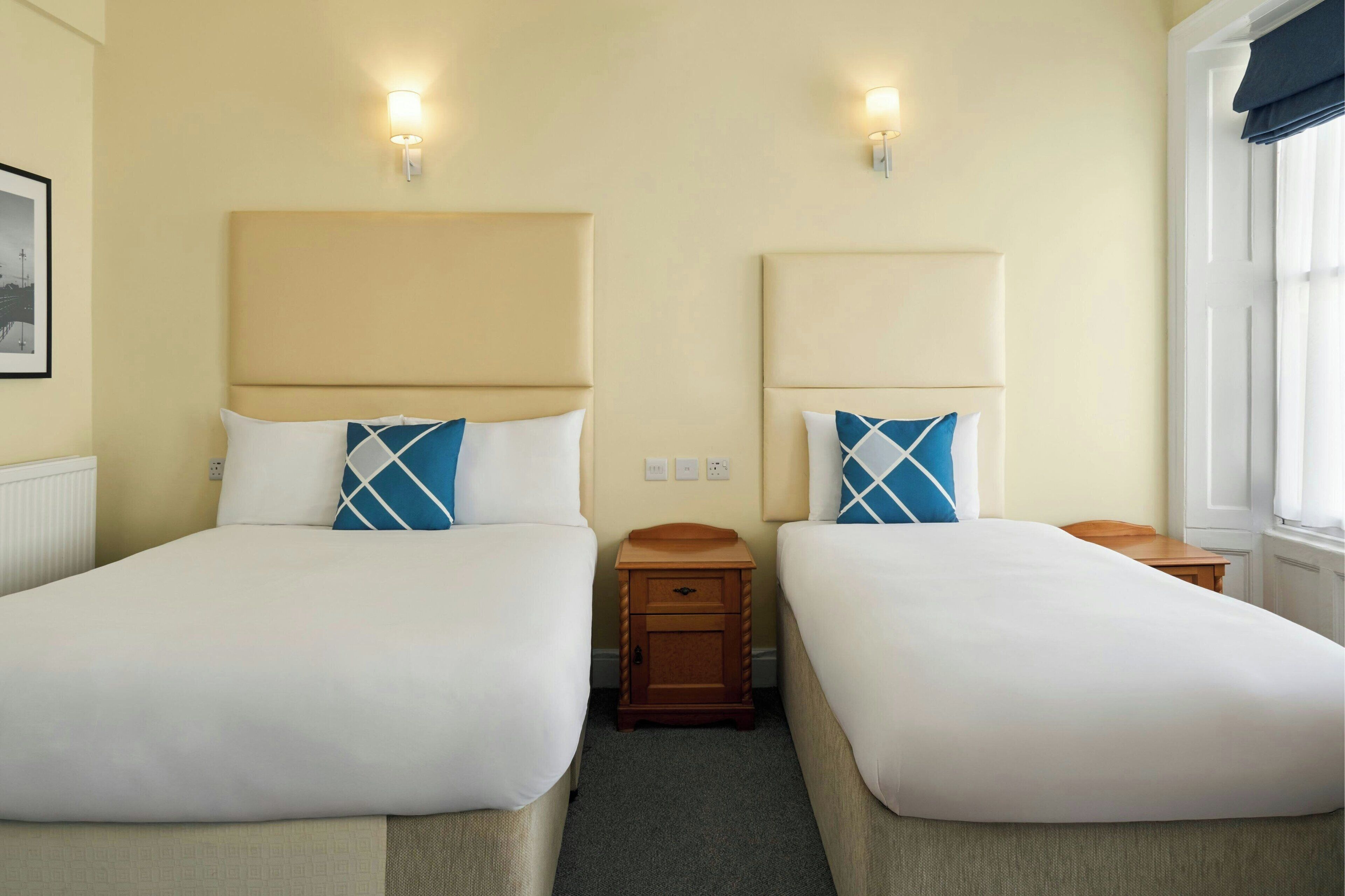 Una habitación de hotel con dos camas, cada una con cabecera y mesitas de noche.