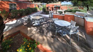 An outdoor patio with a grill, seating, and a pathway leading to a building. - TownePlace Suites by Marriott Tucson (Tucson)